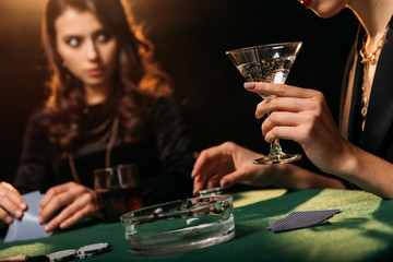 cropped image of girl playing poker and holding glass of cocktail in casino
