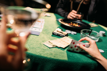 cropped image of women playing poker together at table in casino - obrazy, fototapety, plakaty