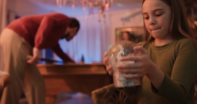 Little girl shakes her snow globe at a Christmas party in slow-motion.