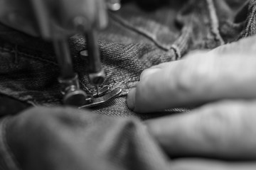 Obraz na płótnie Canvas Closeup hands of Tailor man working on old sewing machine. jeans cloth fabric textile in shop, Tailoring, close up.