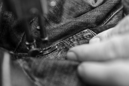 Closeup hands of Tailor man working on old sewing machine. jeans cloth fabric textile in shop, Tailoring, close up. - Powered by Adobe