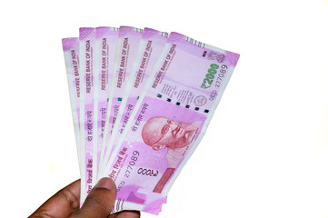 Selective Focus: Hand holding Indian 2000 rupee notes against white background. Close up of the new...