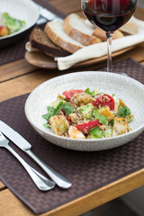 Tabbouleh salad with quinoa, tomatoes, cucumbers and parsley served by chef on terrace with a glass of wine