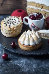 Set of various restaurant desserts on black board. Different sweet snacks, berries