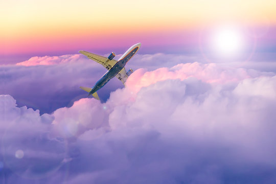 Fototapeta Beautiful sunset sky above clouds with a plane moving upwards. Tourism and travel image.