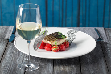 Tasty baked fish with cherry tomatoes, spices on dark rustic background. Grilled delicious fish. Diet and healthy food.