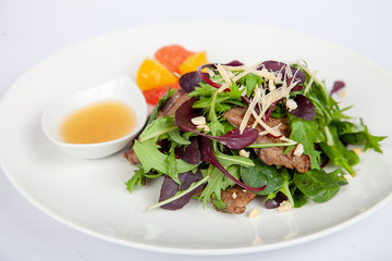 Meat, fish, salads on the table in white plate in the interior with olive oil