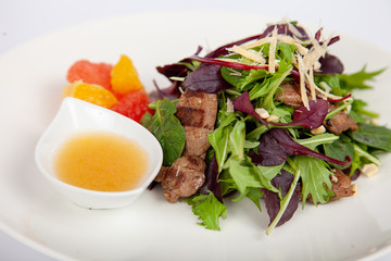 Meat, fish, salads on the table in white plate in the interior with olive oil