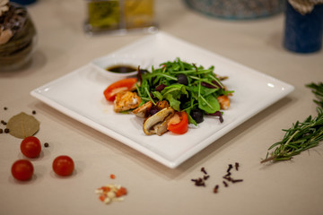 Meat, fish, salads on the table in white plate in the interior with olive oil