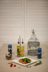 Meat, fish, salads on the table in white plate in the interior with olive oil