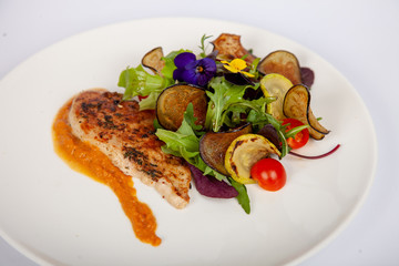Meat, fish, salads on the table in white plate in the interior with olive oil