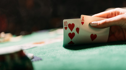 cropped image of woman playing poker and holding cards in casino