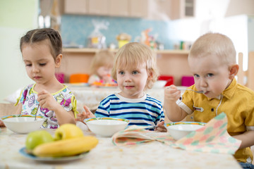 Obraz na płótnie Canvas Kids eating in kindergarten or day care centre
