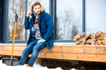 Portrait of a handsome man in winter clothes filling cold sitting on the terrace of the modern house