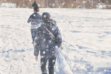 Fototapeta na wymiar Two teen boys walk with ski in the park in the winter snowfall. Concept of friendships