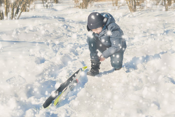 Fototapeta na wymiar Teen boy on skis in the park in the winter snowfall.