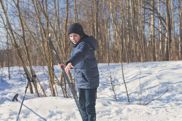 Teen boy on skis in the park in the winter snowfall.