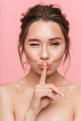 Fototapeta premium Beautiful young woman posing isolated over pink wall background showing silence gesture.