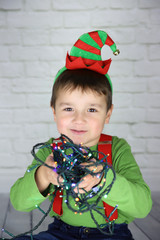 ni&ntilde;o disfrazado de duende con una guirnalda de luces enrollada 