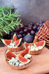 Festive appetizer. Rye flour tarts with gorgonzola cheese, fig fruit slices and honey. Healthy food concept. Perfect combination of cheese, fruits and honey syrup.