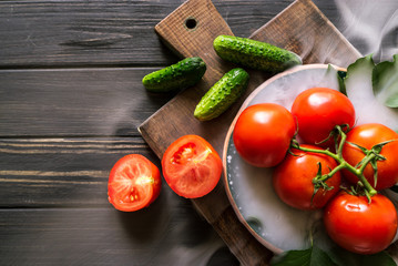 CUCUMBERS, tomatoes on a black wooden background