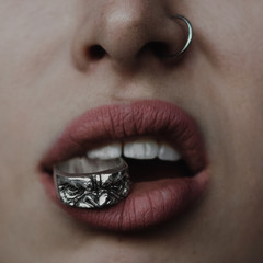 Close up of woman lips with silver ring in her teeth