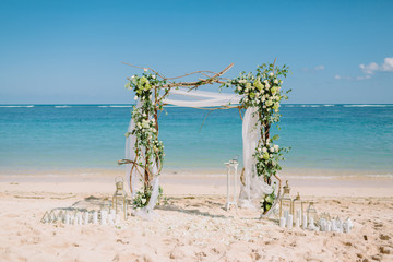 Wedding arch with white flowers at blue ocean in tropical island. Wedding ceremony.