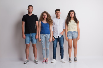 Joyful young group of friends standing in a studio, looking at camera.