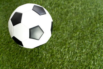 Fototapeta premium Football ball on green grass field background.