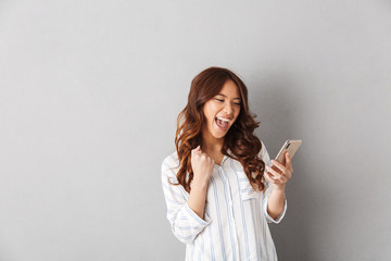 Cheerful asian woman standing isolated over gray