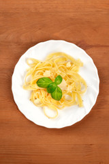 A photo of a plate of Italian pasta with Parmesan cheese and basil leaves, shot from above with copy space