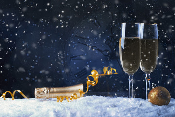 Glasses with champagne against vintage clock close to midnight
