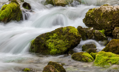 water flowing over rocks filled with moss