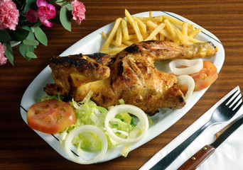 Plato combinado con medio pollo al grill, patatas fritas y ensalada.