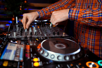 Dj mixes the track in the nightclub at party. In the background laser light show