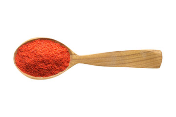 adjika powder in wooden spoon isolated on white background. spice for cooking food, top view.