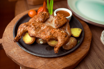Butterflied roasted chicken with lemon, tomatoes and rosemary herbs on rustic wooden table, delicious Thanksgiving or Sunday dinner