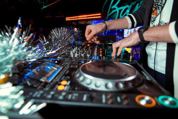 Naklejka premium Dj mixes the track in the nightclub at party. In the background laser light show