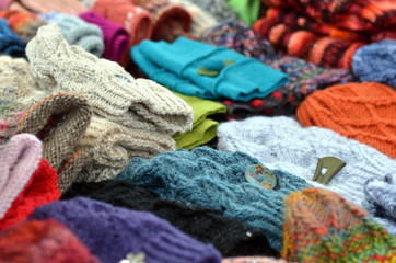 Viele bunte selbst gemachte M&uuml;tzen und Handschuhe aus Wolle in einer Auslage
