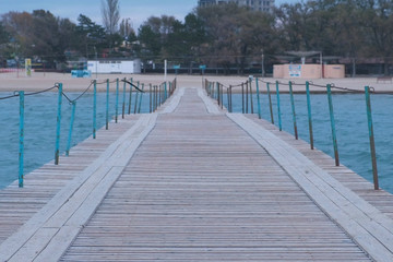 View from the sea pier to the coastal town and sandy beach in evening.