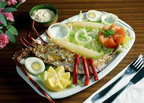 Bandeja con media langosta y una ensalada.