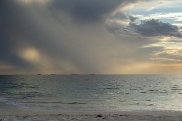 Naklejka na ściany i meble Landscape of a sunset at the beach while raining clouds