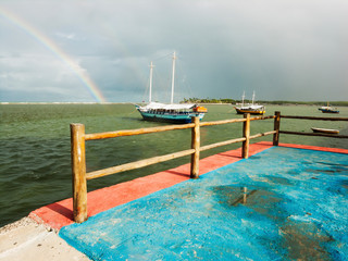 Boats sailing towards a rainbow in the sea
