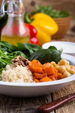 Healthy salad bowl with baked pumpkin,  chickpeas, quinoa, arugula, walnuts
