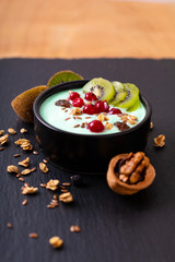 Healthy food colorful Yogurt Breakfast Bowl  with kiwi, flax seeds, Granola, and red currants in black ceramic bowl with copy space