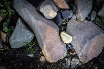 A pile of Gold nugget grains, on big river stone. Golden texture.