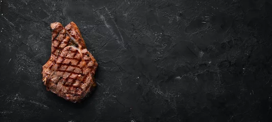Keuken spatwand met foto Kalfslapje vlees op een bot op een zwarte achtergrond. Vrije ruimte voor uw tekst. Bovenaanzicht. © Yaruniv-Studio