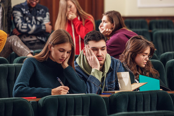 Fototapeta premium The group of cheerful students sitting in a lecture hall before lesson. The education, university, lecture, people, institute, college, studying, friendship and communication concept