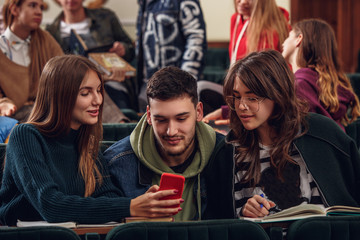 The group of cheerful students sitting in a lecture hall before lesson. The education, university, lecture, people, institute, college, studying, friendship and communication concept