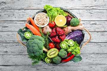 Fresh vegetables and fruits in a wooden box on a white wooden background. Organic food. Top view....